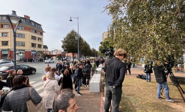 Des dizaines de personnes attendent pour déposer un mot ou une fleur au lycée Gambetta à Arras.