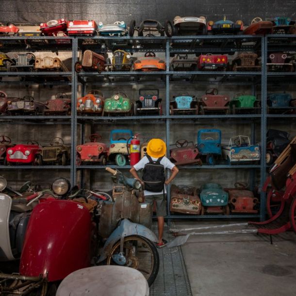 Rear view of a young boy looking at an old car toys.