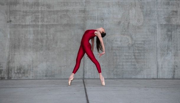 Danseuse de ballet dansant dans la rue, vêtue d'un body rouge et de chaussures de pointe, à Lyon, en France.