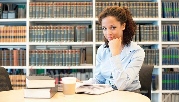 Jeune juriste lisant à un bureau dans une bibliothèque de droit.