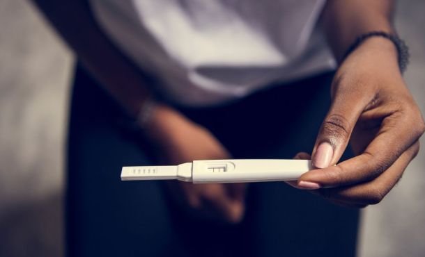 Une femme tient dans ses mains un test de grossesse